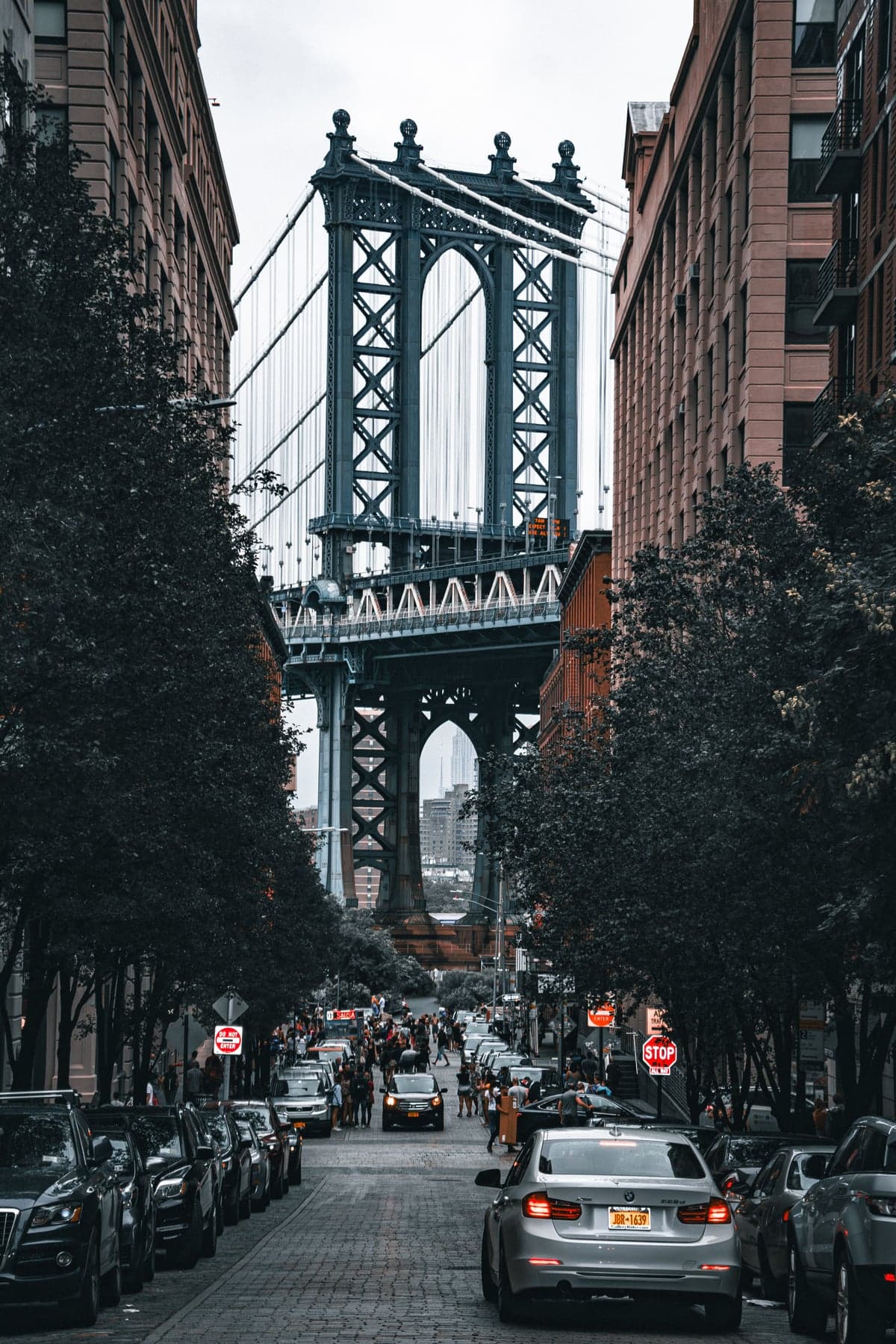 The Manhattan Bridge framed by brick buildings above a cobblestone street in Brooklyn